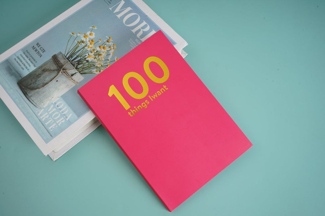 Pink goal journal notebook with yellow '100 things I want' on cover