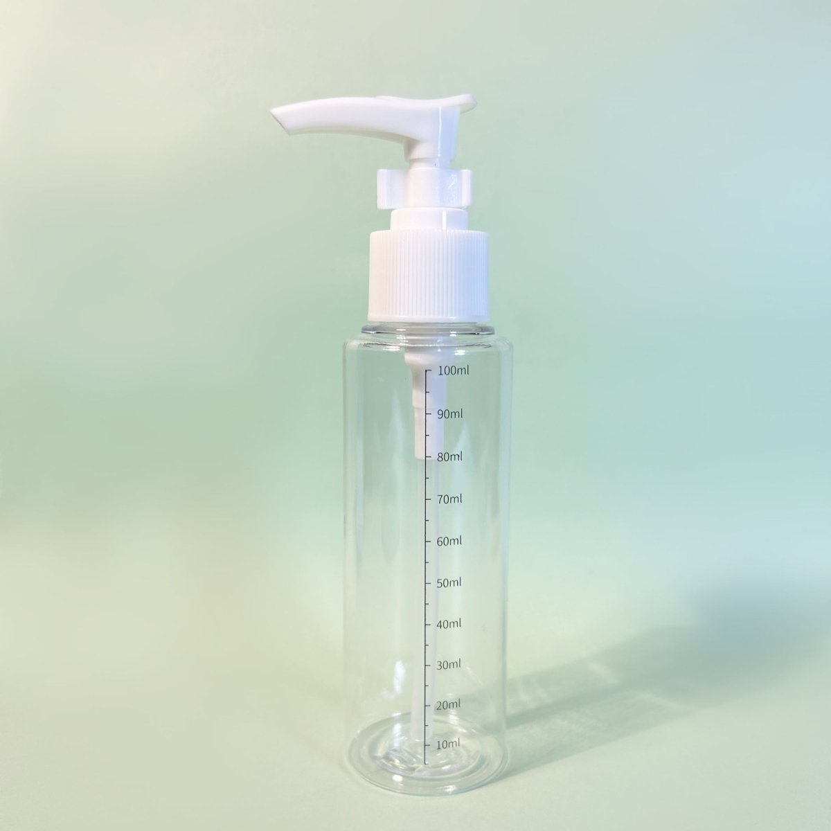 Clear plastic pump bottle, white dispenser head and front measurement scale up to 100ml.