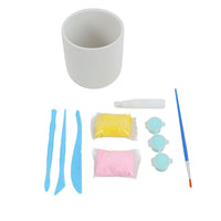 White craft pot with paint packets, blue ribbon strips, brush and mixing tool