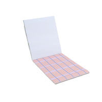 Memo pad open to blank sheets with pink and blue grid pattern pages