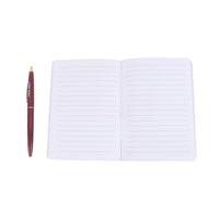 Open white lined notebook with maroon pen beside it