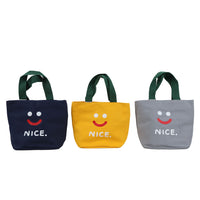 Three smiley lunch bags in navy, yellow, and gray with green handles