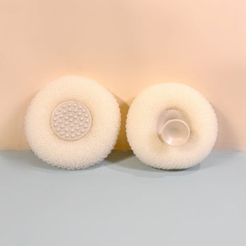 Cream cleaning sponges with textured circular scrub pads; one has a plastic soap reservoir.