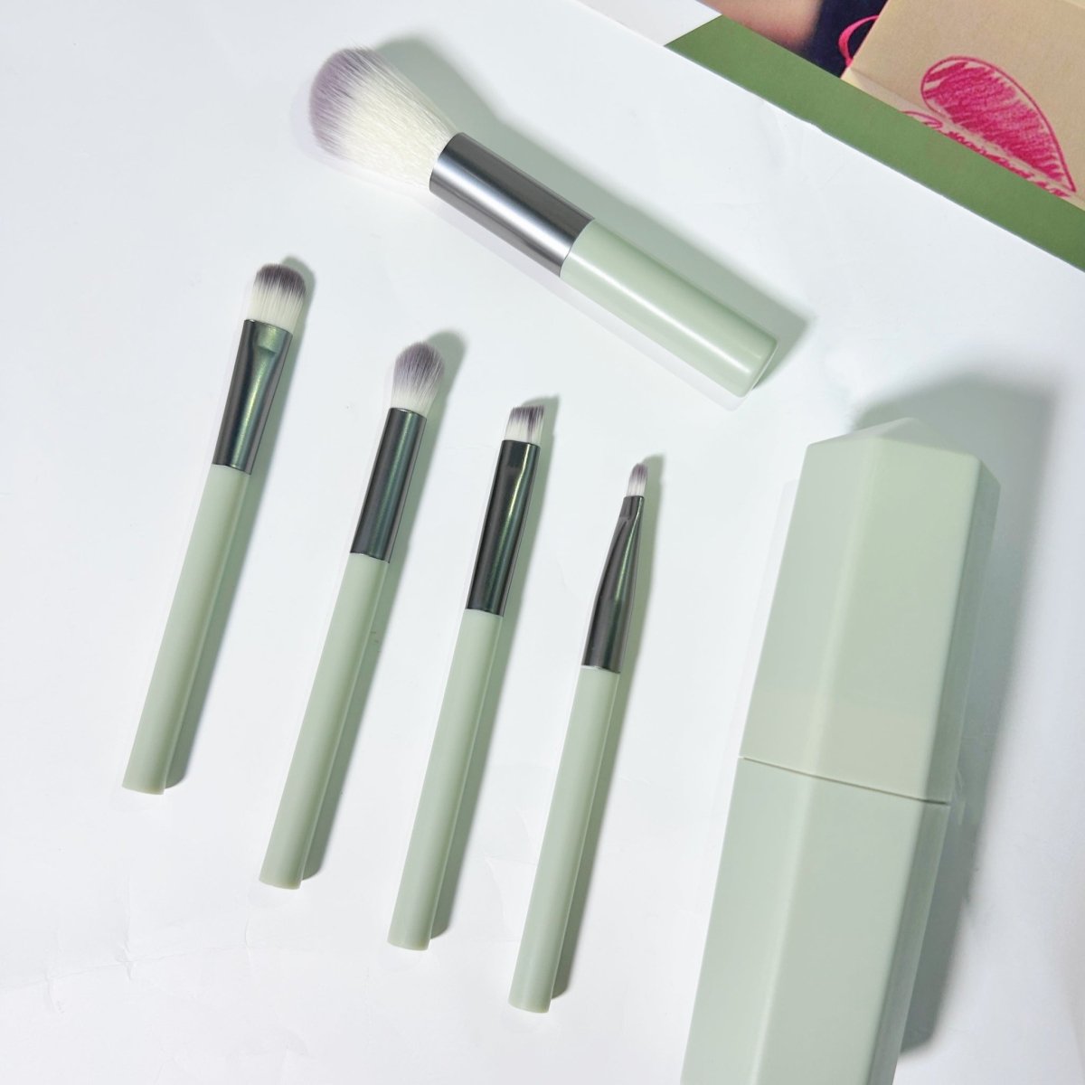 Makeup brush set with five mint-handled brushes and a rectangular storage case