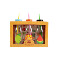 Three fruit-decorated milk bottles with colored straws in a display box