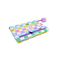 Folded notebook with colorful pixel-pattern cover and purple pom-pom tassel