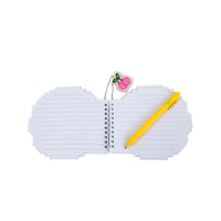 Open lined memo pad with yellow pen and hanging pink acrylic pendant