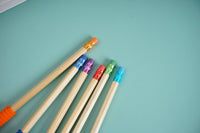 Colored wooden pencils with red, purple, teal and orange barrels, sharpened tips