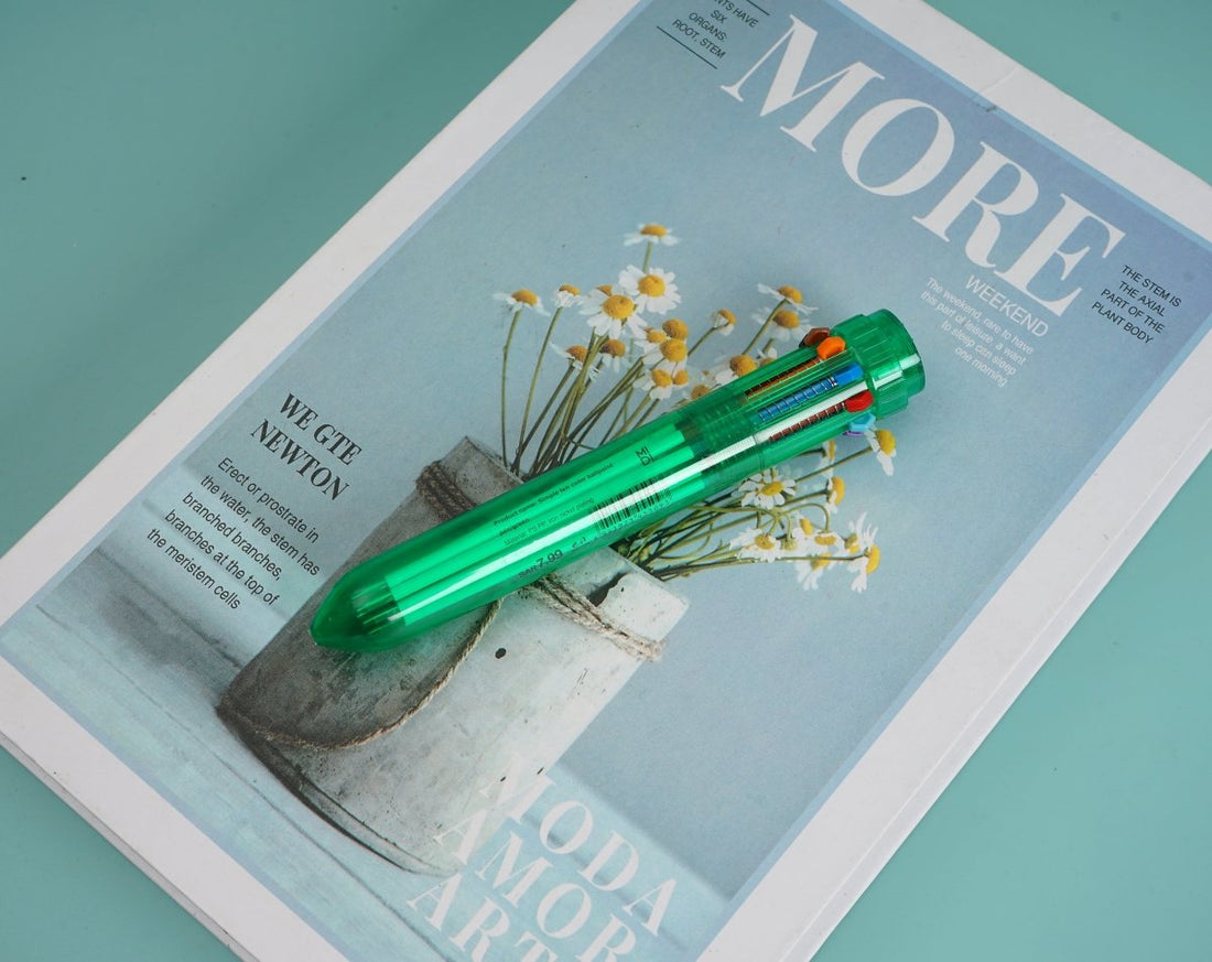 Green 6-in-1 multi-color pen with clip, resting diagonally on a book