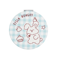 Round compact mirror with blue plaid background and outlined hungry puppy illustration