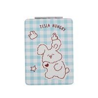 Square double-sided compact mirror with light blue gingham cover and puppy “TESLA HUNGRY” text
