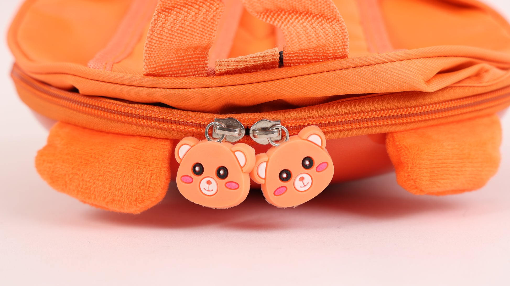 Orange hard shell kids backpack zipper pull with two pink bear charm faces