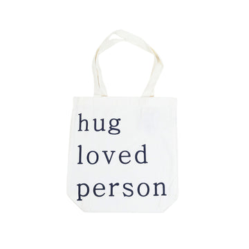 White canvas tote bag with handles, 'hug loved person' lettering in black and green