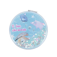 Light blue round portable mirror with glitter, "I love the ocean" text, and seashells