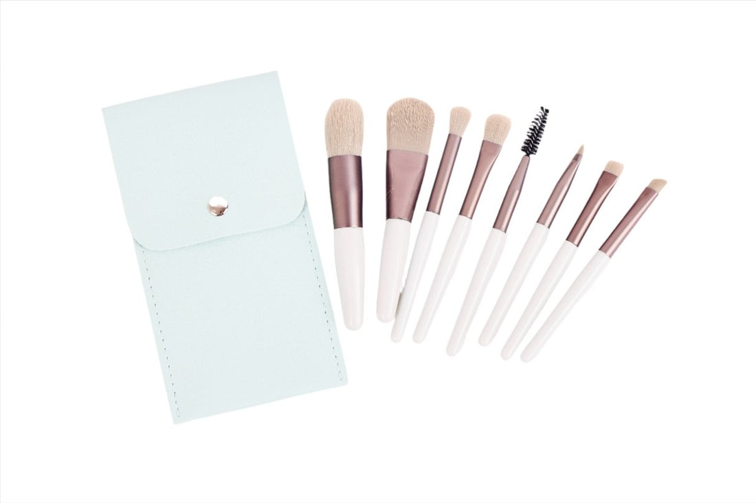 Makeup brush set with 7 brushes and mint flip-top pouch, rose-gold ferrules, white handles.