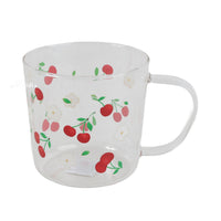 Clear glass cup with red cherry and green leaf fruit print, curved handle