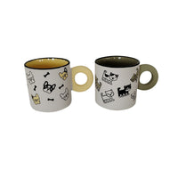 Two ceramic cups with cute animal icons and cream handles, dark inner rims