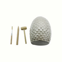Stone fossil egg with textured scales and three wooden excavation tools