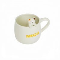 White ceramic mug with cat topper figurine and yellow 'MEOW' print.