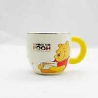 Cream Winnie the Pooh cup with yellow handle and Pooh character illustration