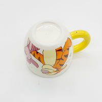 Cream mug with yellow handle and Tigger graphic on side near the rim