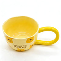 Yellow Winnie the Pooh long-handle coffee cup with character faces and logo