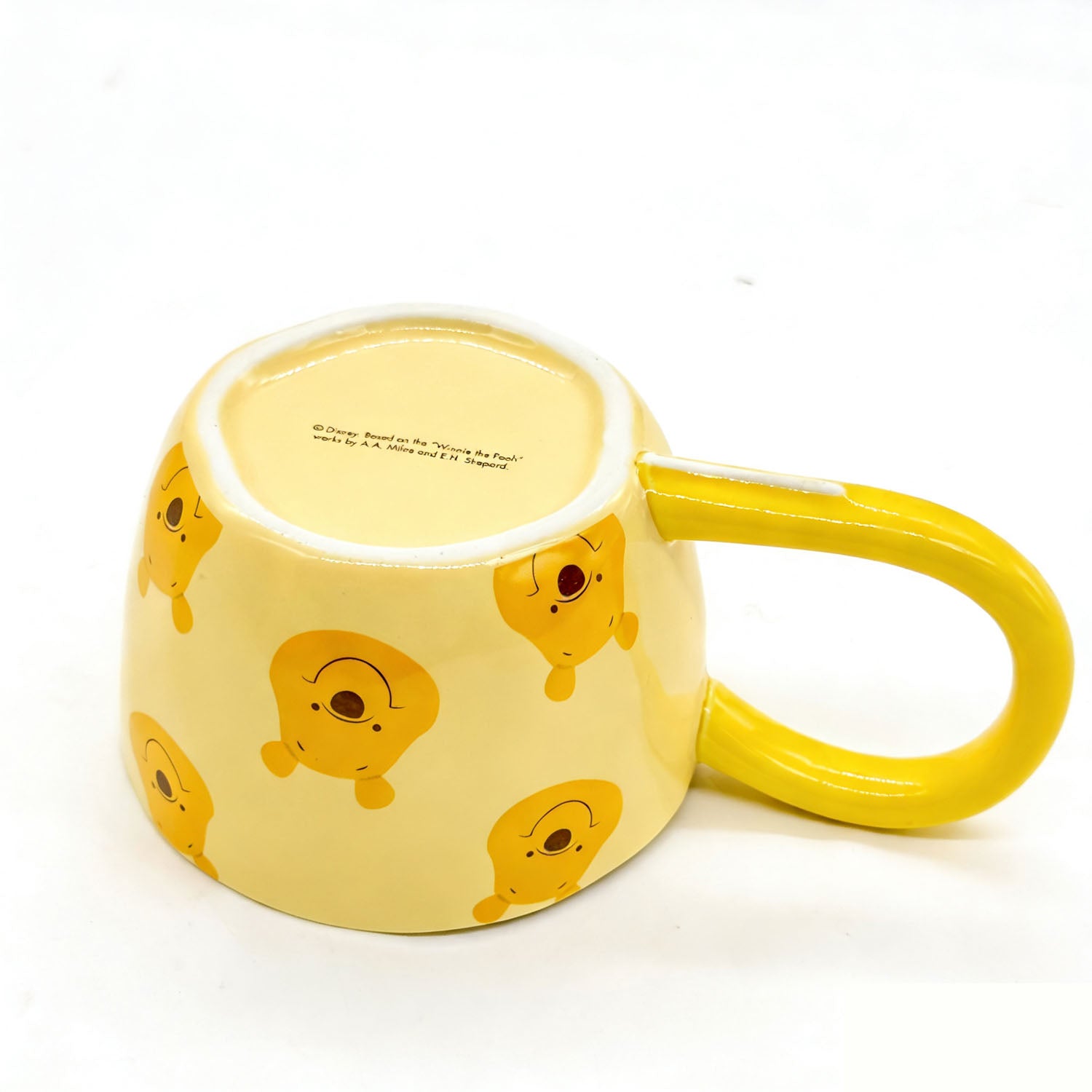 Yellow long-handle coffee cup with Pooh character pattern and inner base text