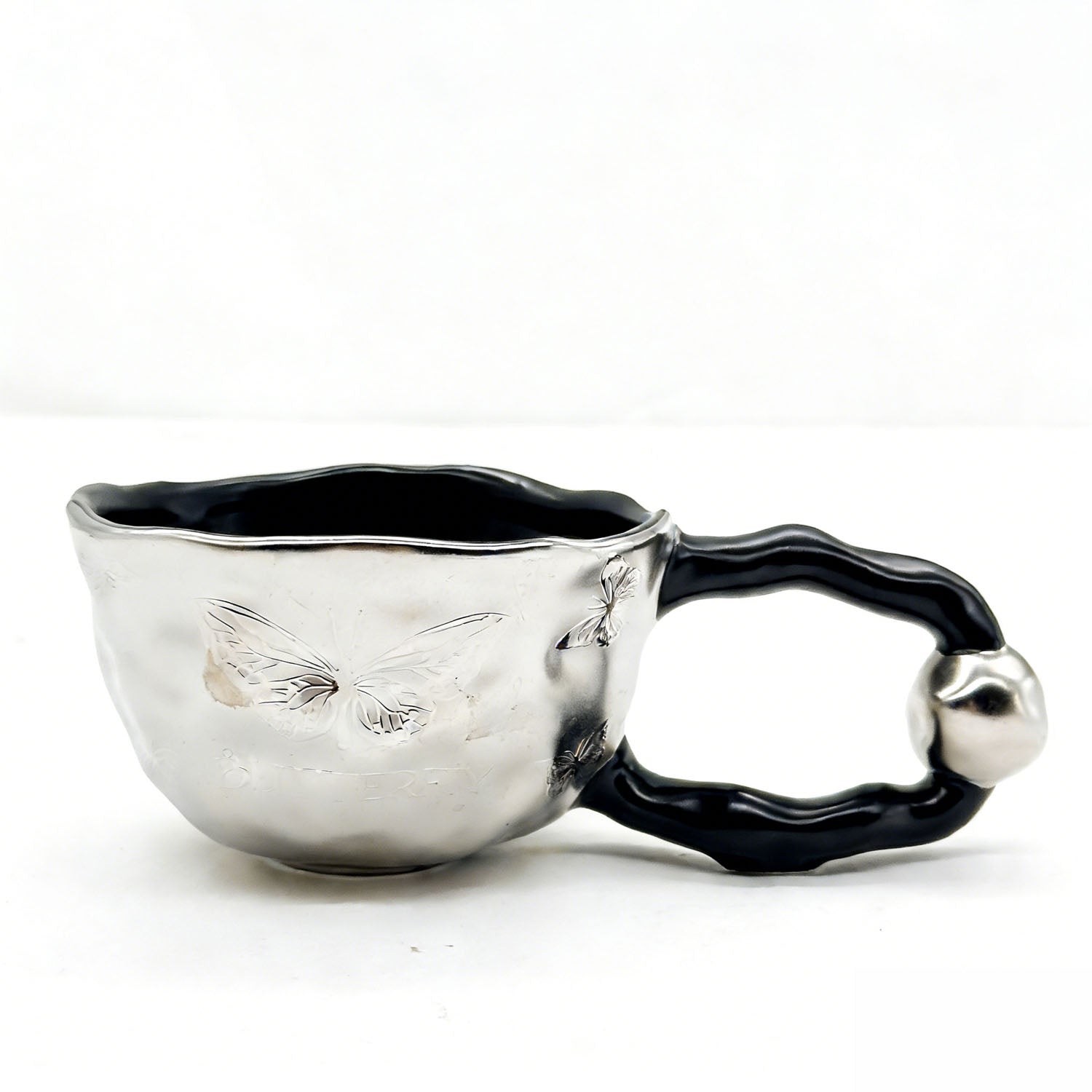 Ceramic cup with butterfly design and irregular rim 2