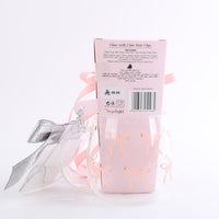 Glass cup gift packaging with silver bow hair clips and pink ribbon