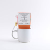 White ceramic mug with back packaging label, cat gift box sleeve and gold ribbon