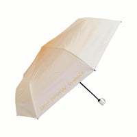 Folding umbrella, light beige canopy with script-style logo and dark handle.