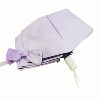 Folding umbrella, light purple canopy with ribbon tie and cream handle.
