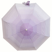 Folding umbrella, lavender canopy with tied bow detail on top and centered hub.