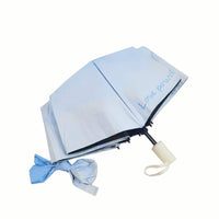 Light blue folding umbrella with bow tied strap and black edge trim, open