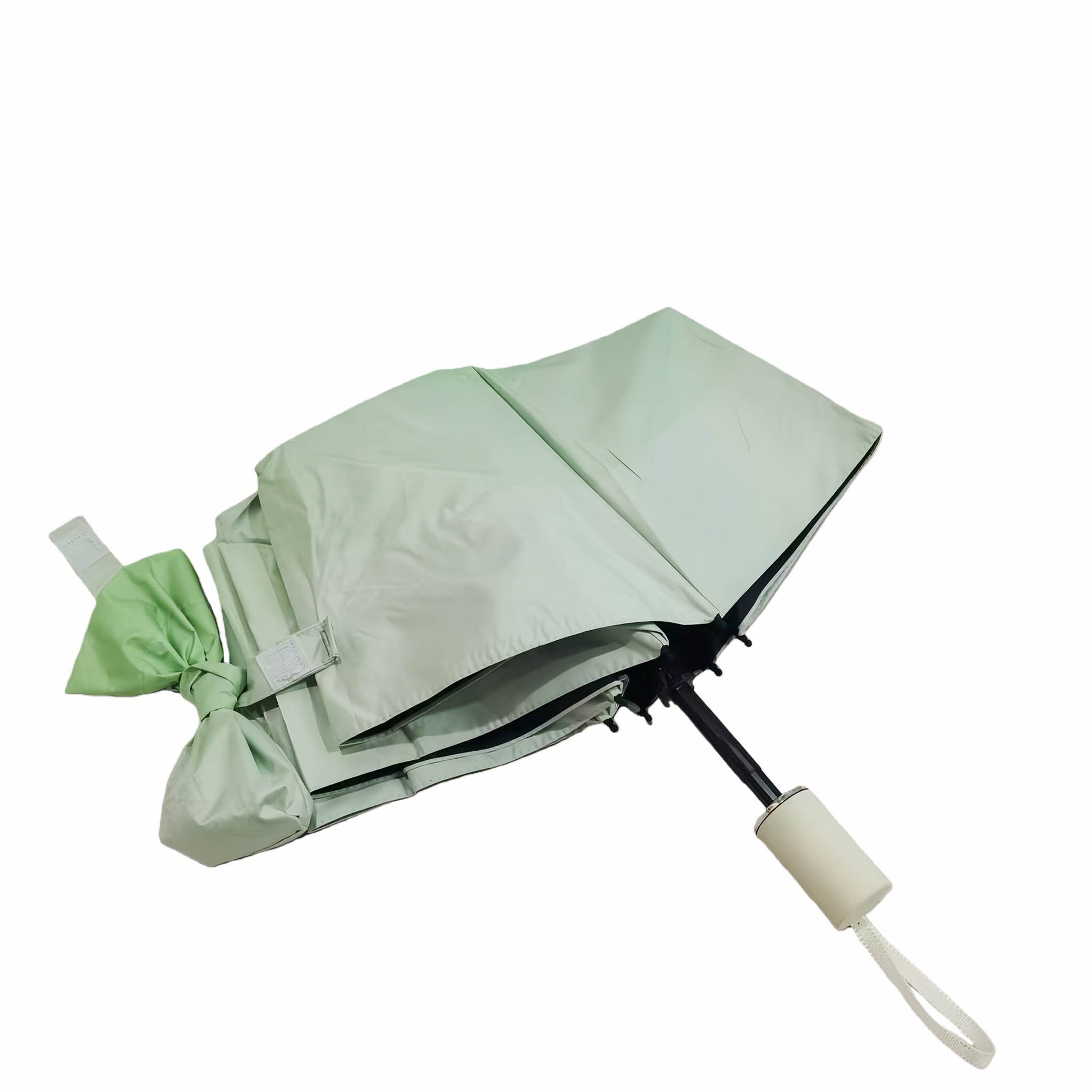 Folding umbrella, light green canopy with ribbon tie and white handle.