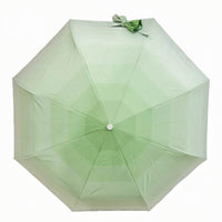 Folding umbrella, pale green canopy with tied bow on top and centered hub.
