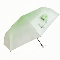 Folding umbrella, mint green canopy with ribbon bow and white handle.