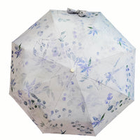 Folding umbrella with white fabric and blue floral pattern, open canopy with center button