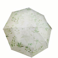 Folding umbrella with white fabric and green floral pattern, round button center