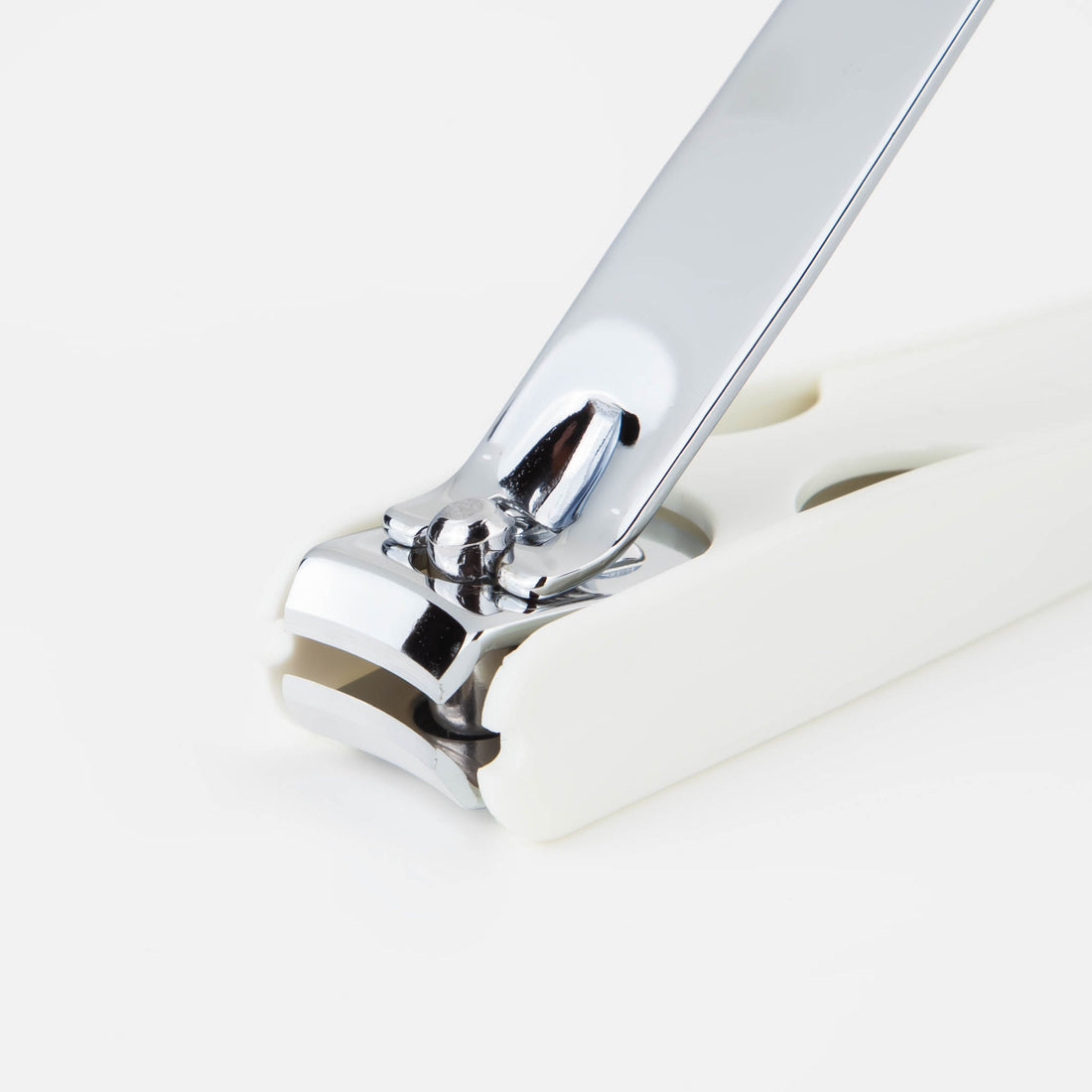 Metal nail clipper with chrome blades and curved handle, off-white base