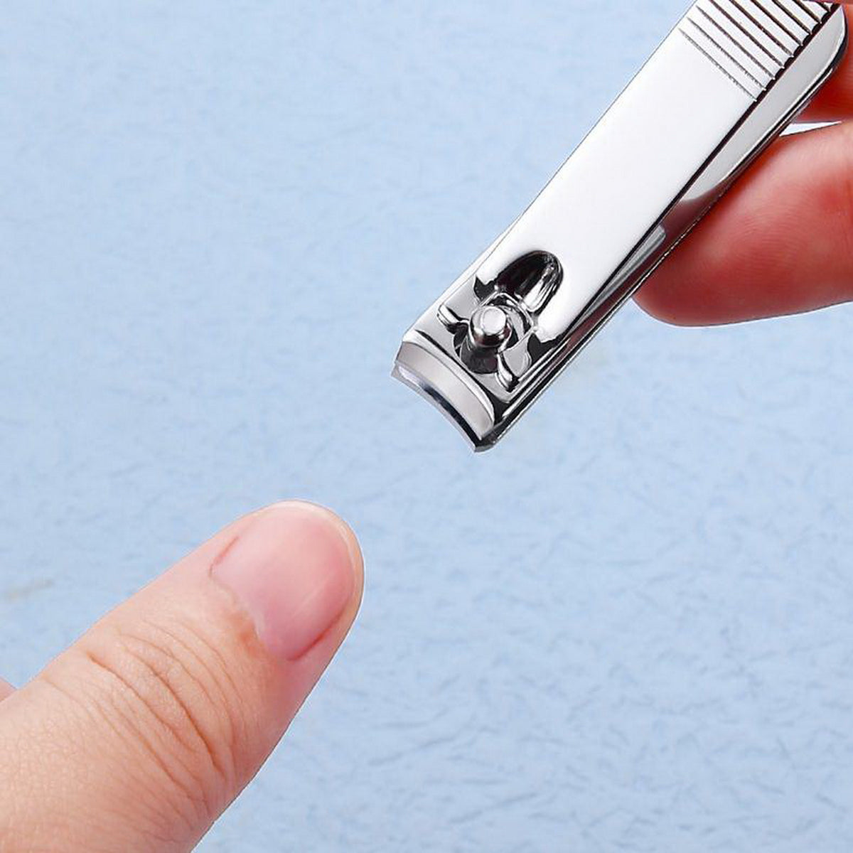 Metal nail clipper tip in hand with cutting lever and open jaws