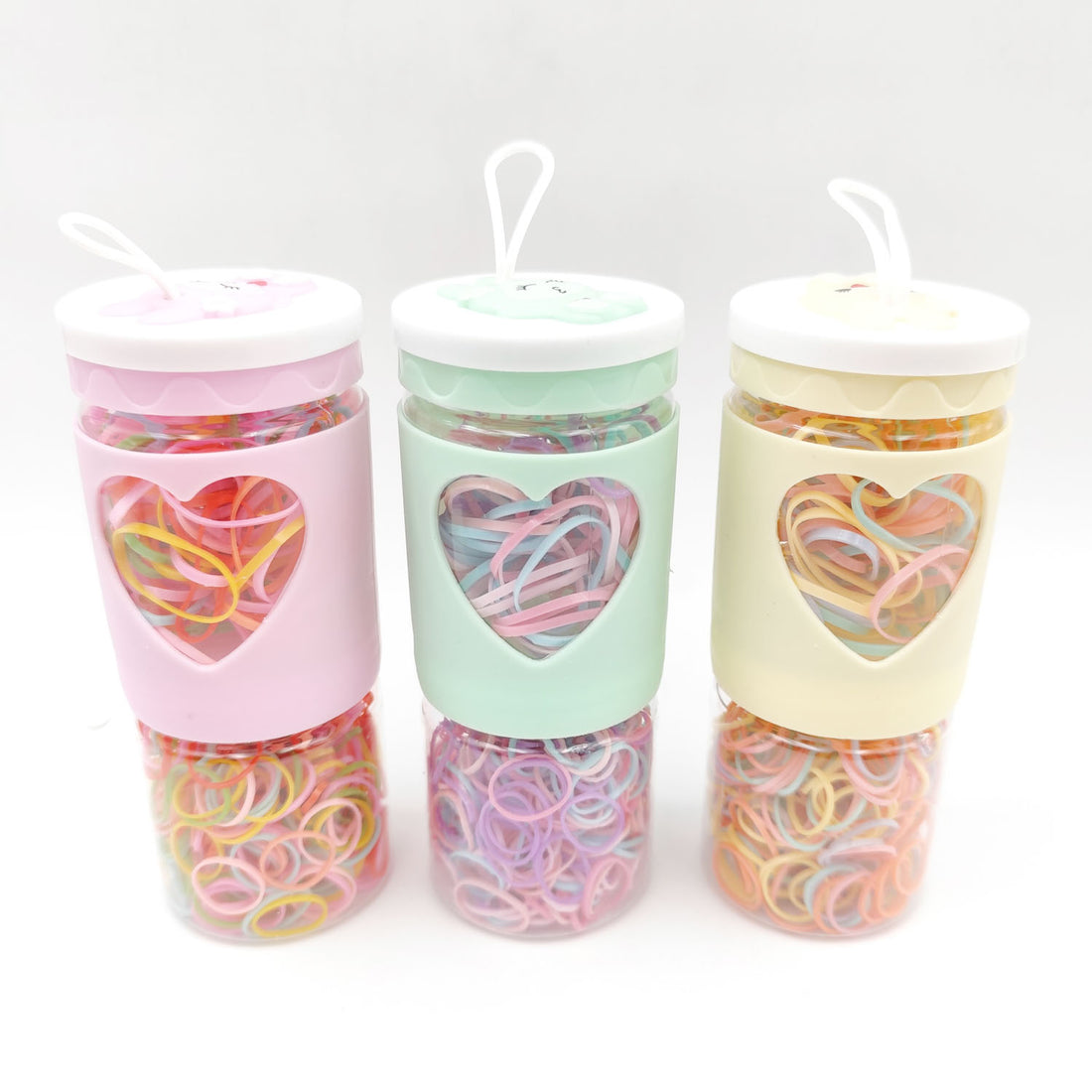 Rubber band set in three pastel cups: pink, mint, and cream, with rainbow bands