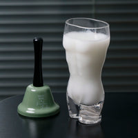 Clear glass shaker cup with white drink and matching green-and-black shaker base