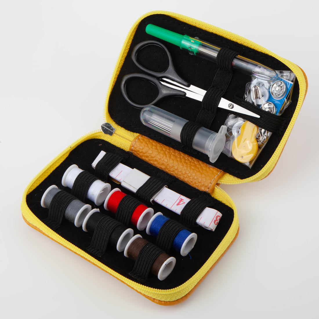 Portable sewing kit in open yellow case with thread spools, scissors, needles, seam ripper