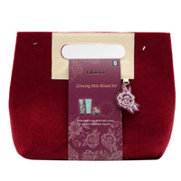 Burgundy felt cosmetic pouch with Bloom label and floral charm, glowing skin set