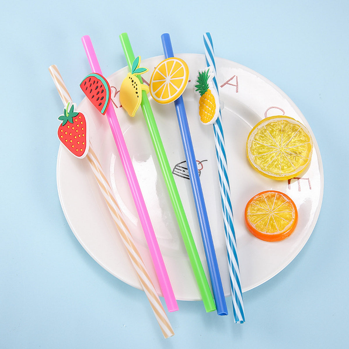Fruit-themed drink straw set on a plate with striped and solid colorful straws.