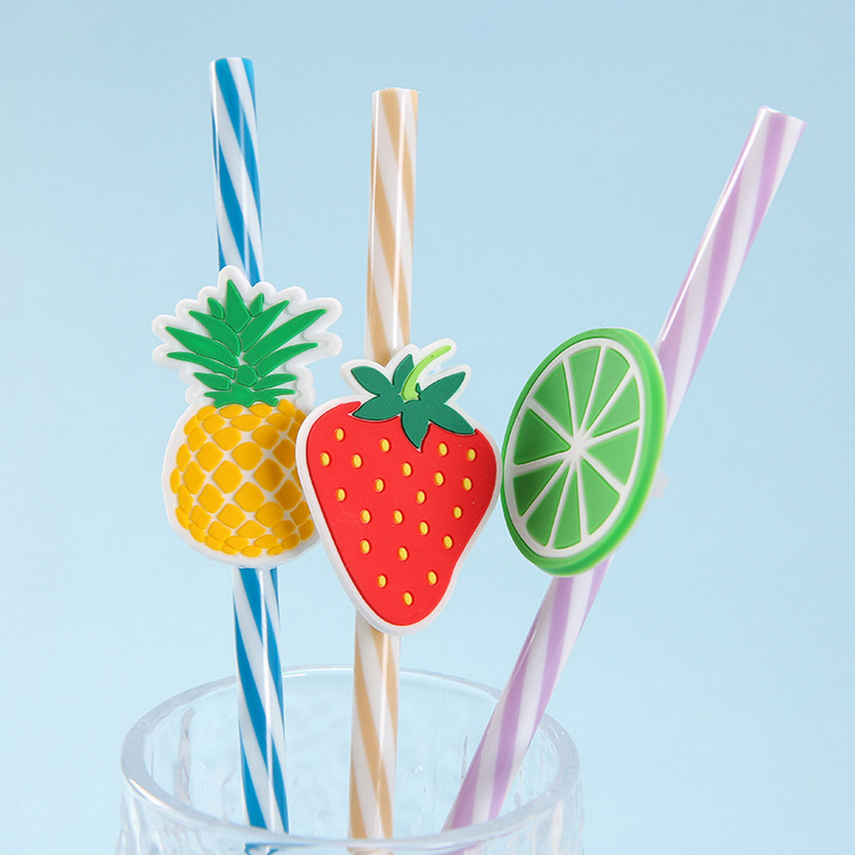 Two fruit-top drink straws with pineapple, strawberry, and citrus cutout toppers.
