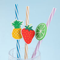 Two fruit-top drink straws with pineapple, strawberry, and citrus cutout toppers.