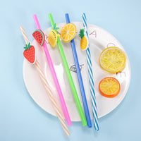 Colorful fruit-top drink straw set on a white plate with citrus and pineapple toppers.