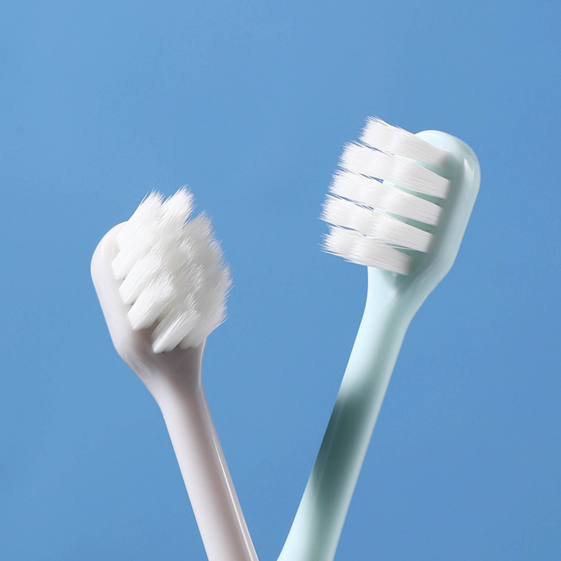 Kids toothbrushes, white and mint handles, with rounded bristle heads
